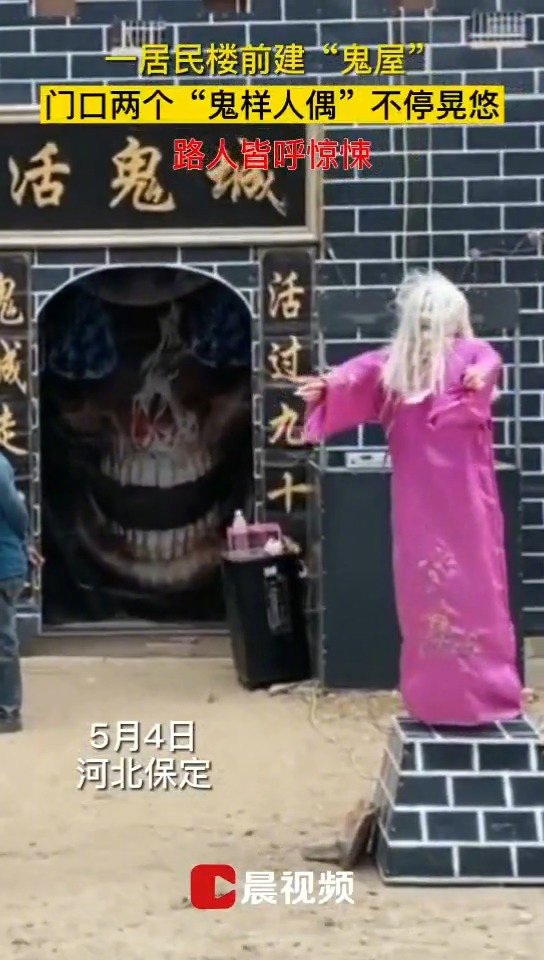 一居民楼前建起一鬼屋,名为"活鬼城",鬼屋门口的两个"恐怖人偶"不停